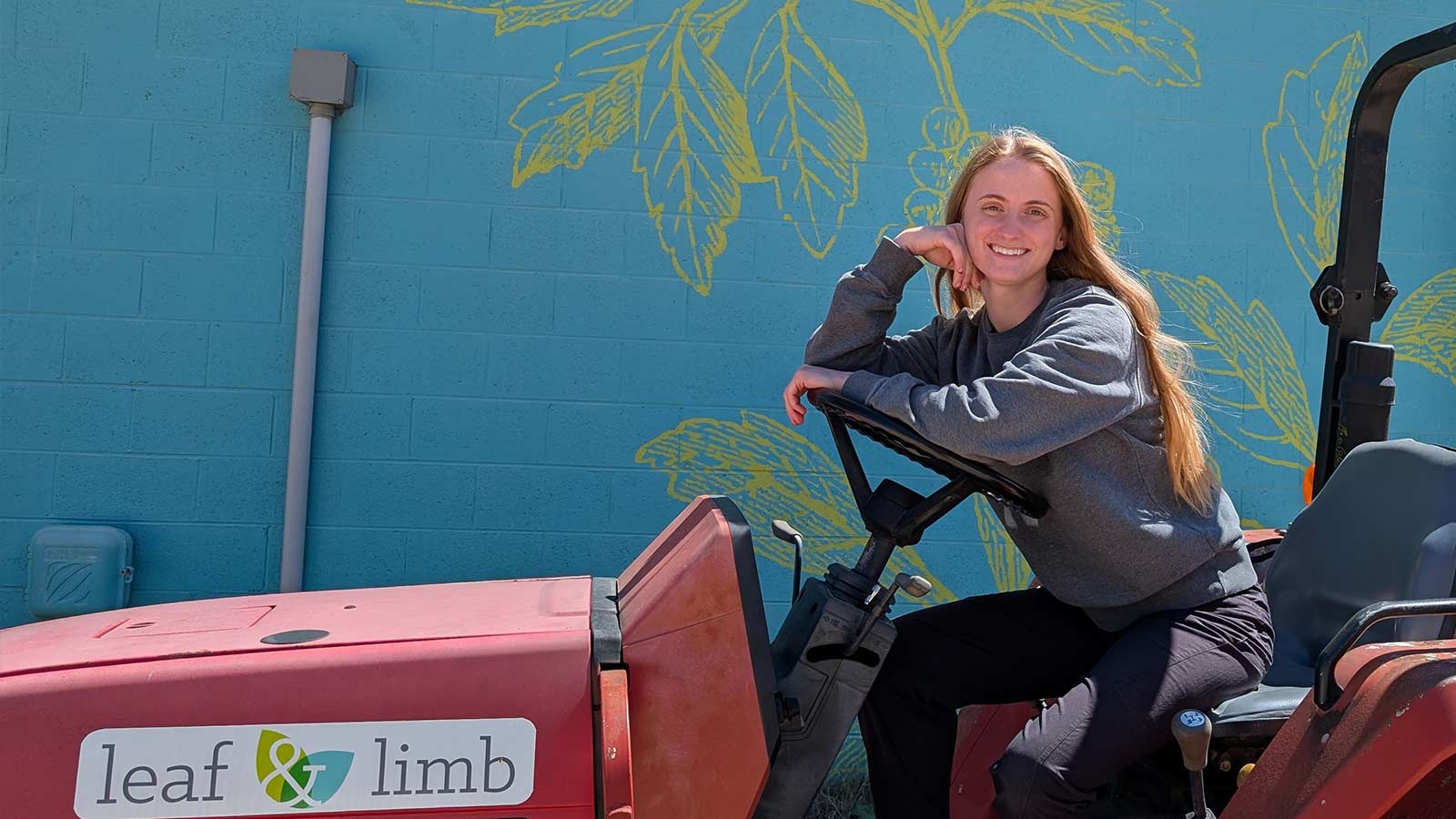 Portrait of Anna smiling outdoors in front of a mural