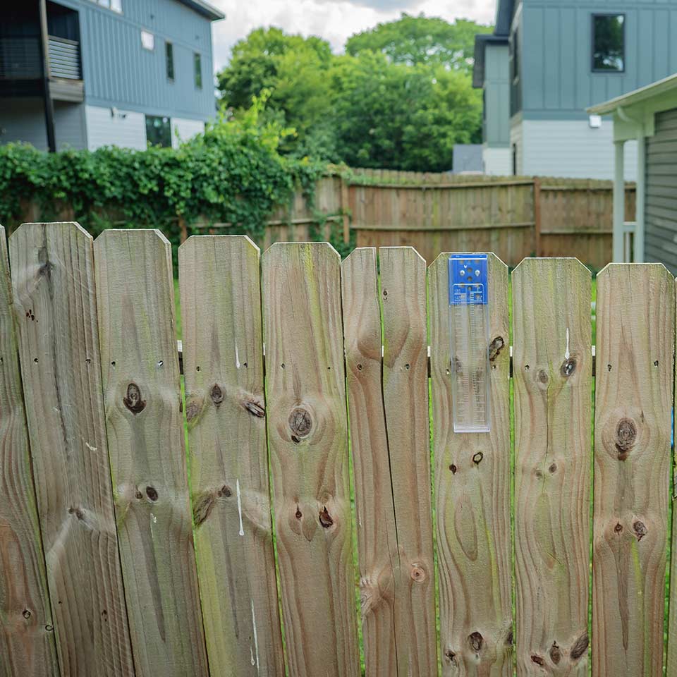 Rain gauge installed on a fence post in a garden